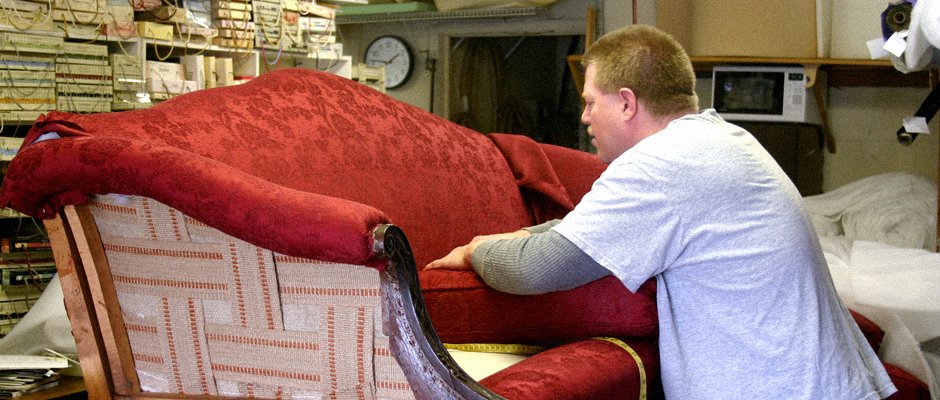 man providing furniture upholstery services on a sofa in his workroom